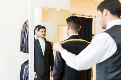 Tailor checking mans suit to see if it requires adjustments